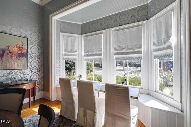 dining area featuring baseboards, wood finished floors, and wallpapered walls