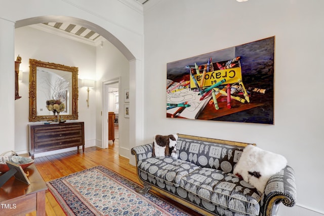 living room with baseboards, arched walkways, hardwood / wood-style floors, and ornamental molding