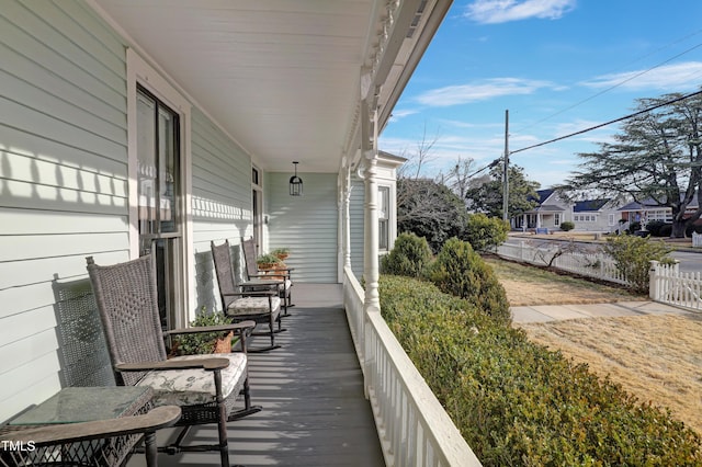 wooden terrace featuring covered porch and fence