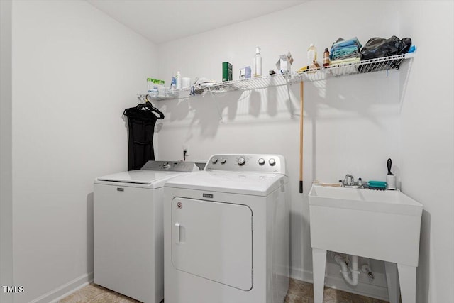 washroom featuring laundry area, baseboards, a sink, and independent washer and dryer