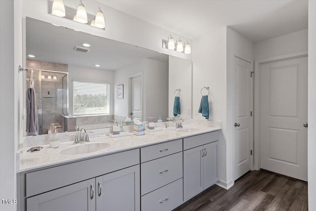 full bath featuring double vanity, wood finished floors, a sink, and a shower stall