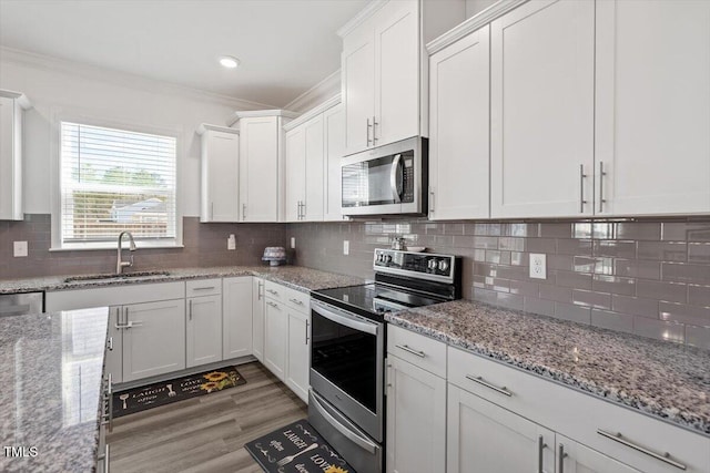 kitchen featuring appliances with stainless steel finishes, white cabinets, crown molding, and a sink