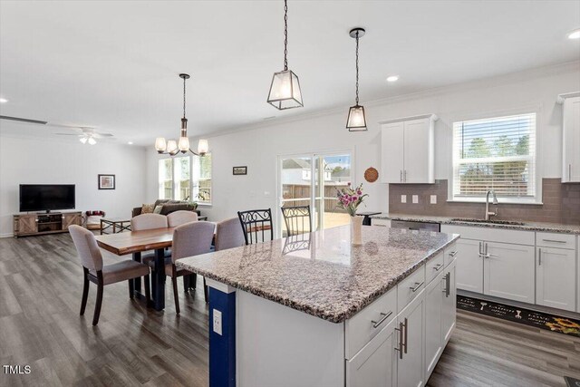 kitchen with plenty of natural light, tasteful backsplash, a center island, crown molding, and a sink