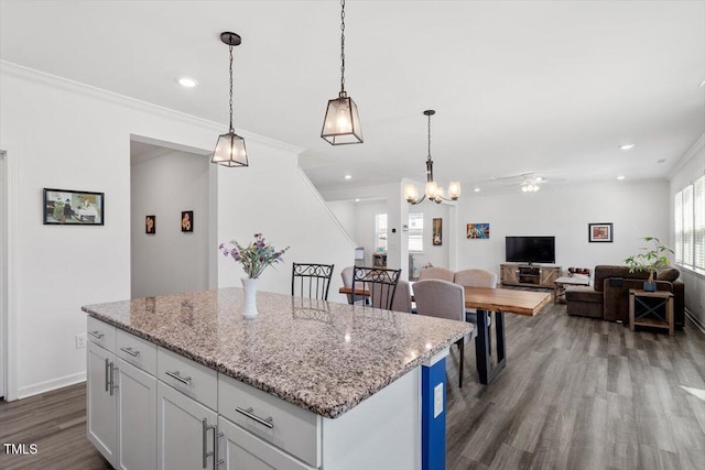 kitchen with a center island, crown molding, hanging light fixtures, white cabinets, and wood finished floors