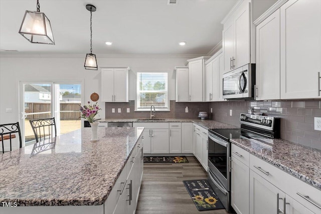 kitchen with decorative backsplash, appliances with stainless steel finishes, ornamental molding, white cabinetry, and a sink