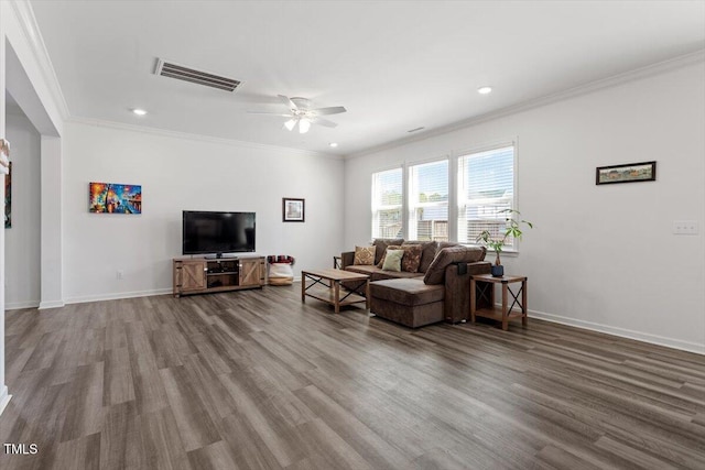 living room featuring baseboards, wood finished floors, visible vents, and crown molding