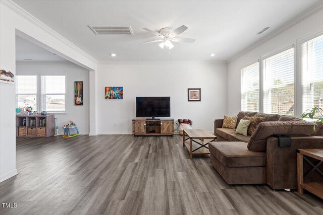 living area with visible vents, wood finished floors, and ornamental molding