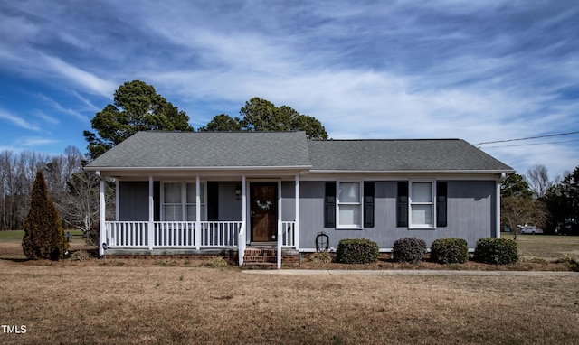 ranch-style home with covered porch, a shingled roof, and a front lawn