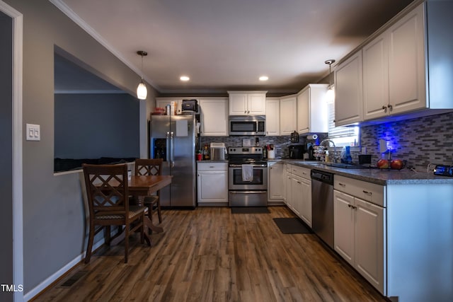 kitchen with dark wood finished floors, dark countertops, appliances with stainless steel finishes, a sink, and backsplash