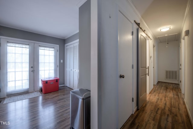 corridor featuring attic access, visible vents, ornamental molding, wood finished floors, and french doors