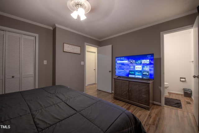 bedroom with a closet, ornamental molding, ceiling fan, ensuite bath, and wood finished floors