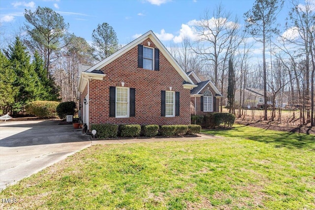 view of front of house featuring driveway, brick siding, and a front yard