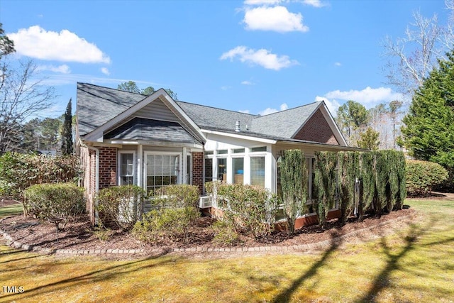 view of front facade featuring brick siding, a front lawn, and a sunroom