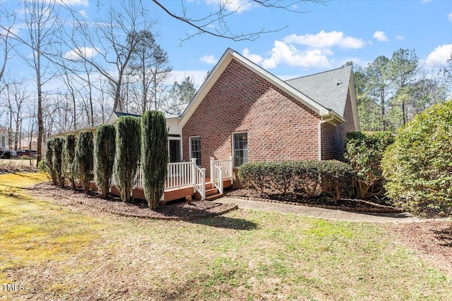 view of side of property with a deck, a yard, and brick siding