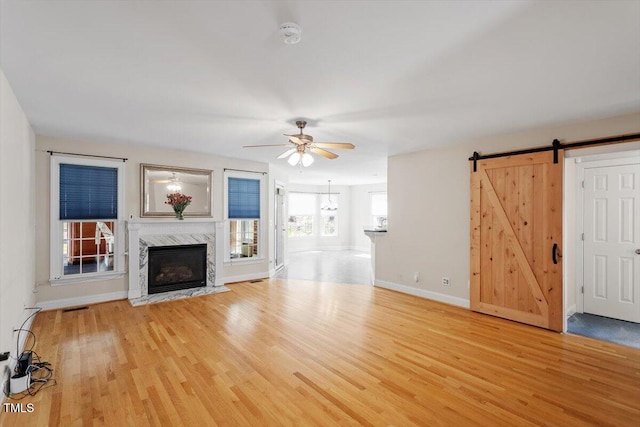 unfurnished living room with baseboards, visible vents, a ceiling fan, a premium fireplace, and wood finished floors