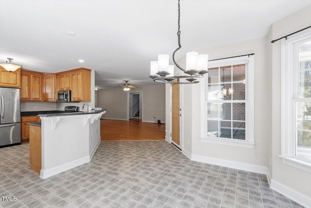 kitchen with stainless steel appliances, dark countertops, open floor plan, a kitchen breakfast bar, and baseboards