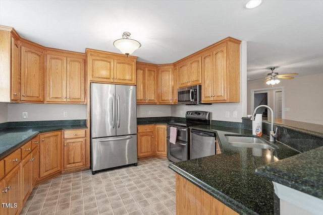 kitchen with recessed lighting, appliances with stainless steel finishes, a sink, ceiling fan, and dark stone countertops