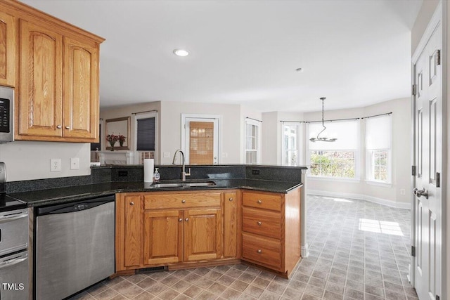 kitchen with a peninsula, appliances with stainless steel finishes, brown cabinetry, and a sink