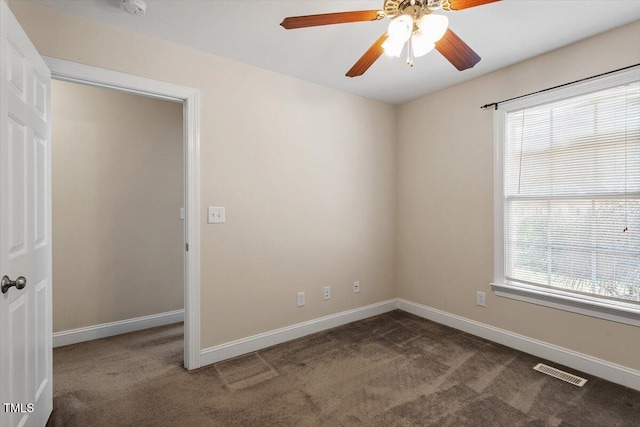 carpeted spare room with baseboards, visible vents, and a ceiling fan