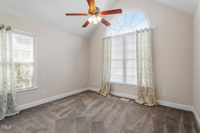 carpeted empty room featuring plenty of natural light, visible vents, vaulted ceiling, and baseboards