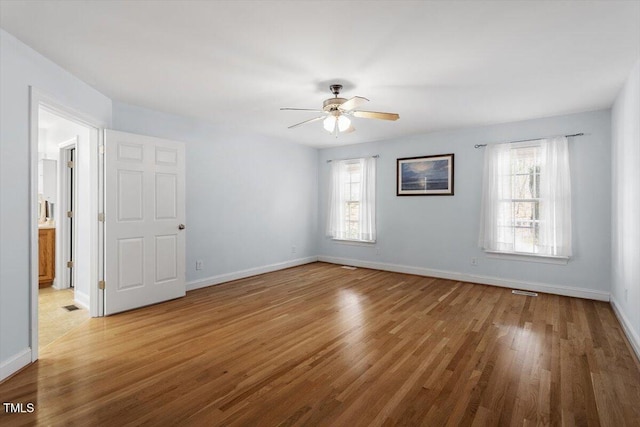 empty room featuring plenty of natural light, baseboards, and wood finished floors