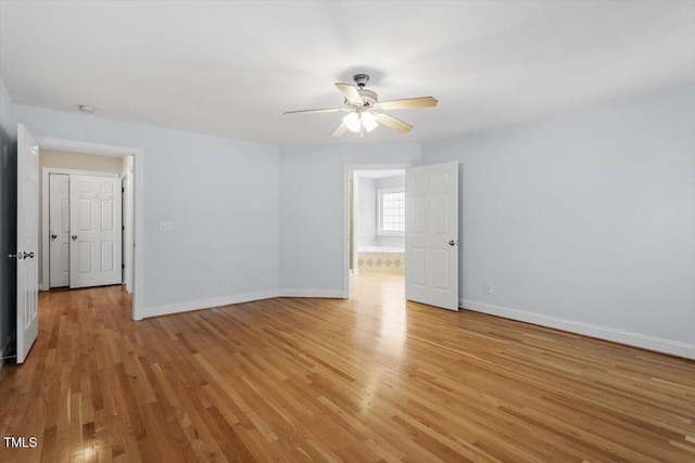 spare room with ceiling fan, light wood-type flooring, and baseboards