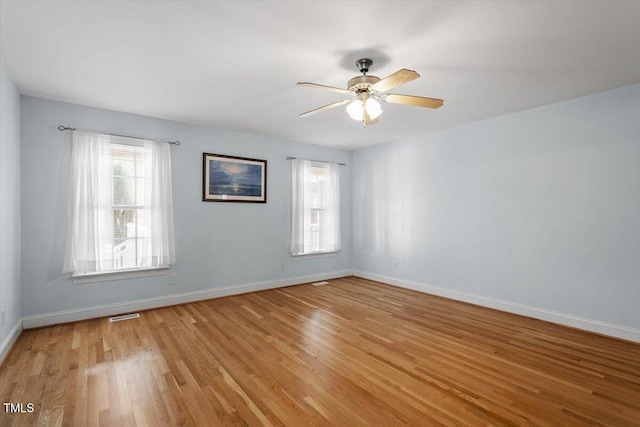 empty room with light wood-style flooring, visible vents, baseboards, and ceiling fan