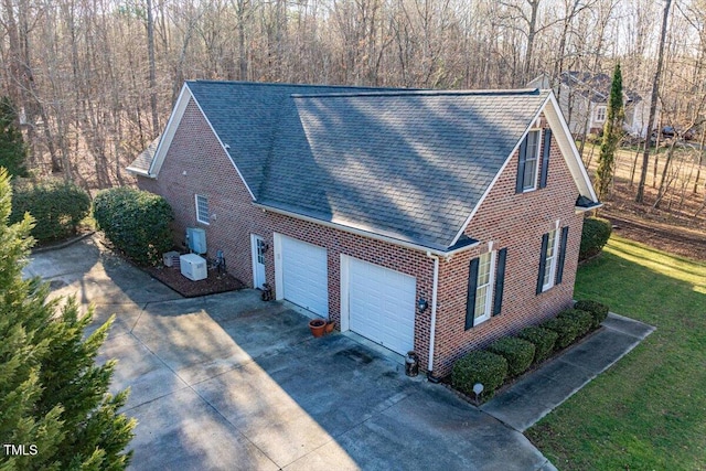 exterior space with concrete driveway, brick siding, an attached garage, and roof with shingles