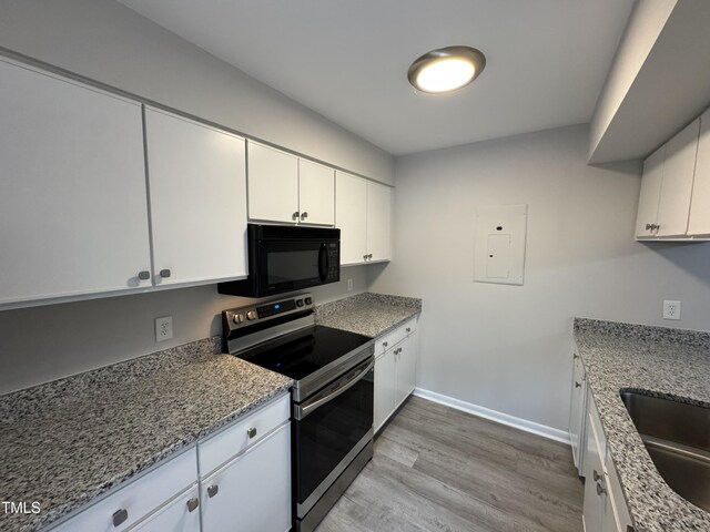 159 Finley Forest Dr, Chapel Hill, NC 27517 - kitchen with black microwave, electric range, light wood-style flooring, electric panel, and white cabinetry