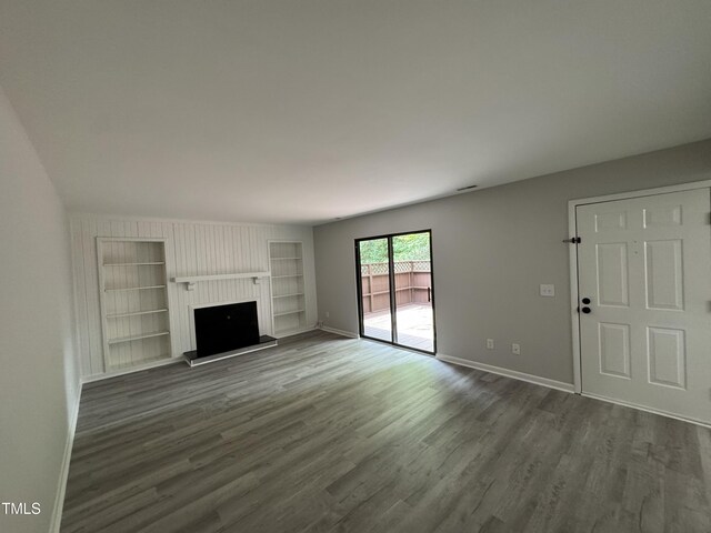 159 Finley Forest Dr, Chapel Hill, NC 27517 - unfurnished living room with built in shelves, dark wood-type flooring, baseboards, and a fireplace with raised hearth