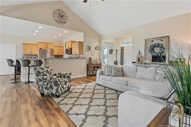 living room with baseboards, light wood-style flooring, ceiling fan, high vaulted ceiling, and recessed lighting