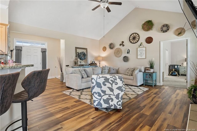 living room featuring baseboards, ceiling fan, high vaulted ceiling, and wood finished floors