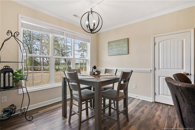 dining room with dark wood-style floors, crown molding, baseboards, and an inviting chandelier