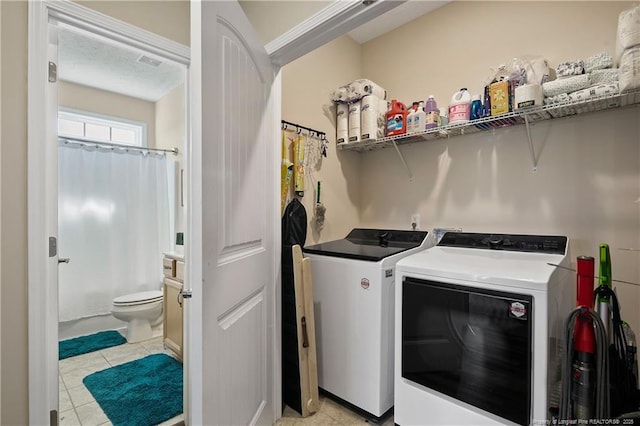 clothes washing area with laundry area, washer and dryer, and light tile patterned flooring