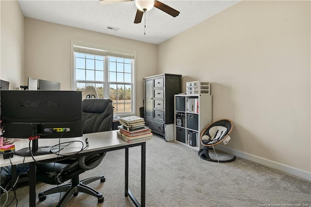 office space featuring baseboards, visible vents, a ceiling fan, and light colored carpet