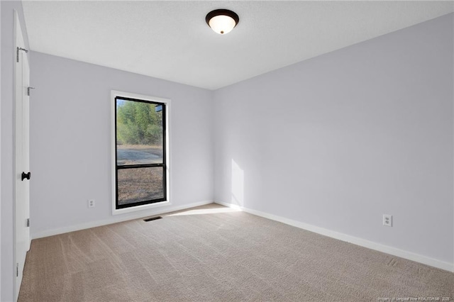 carpeted spare room with visible vents and baseboards