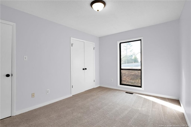 carpeted empty room featuring visible vents and baseboards