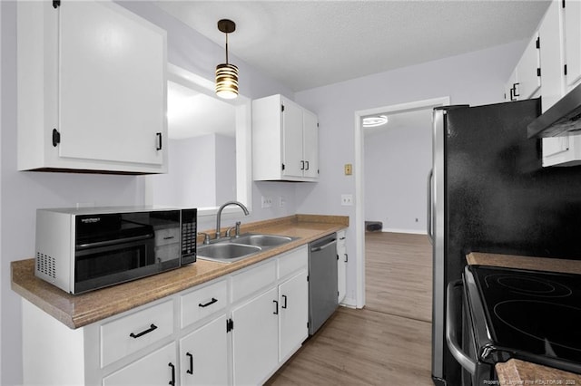 kitchen with light wood finished floors, white cabinets, a sink, black microwave, and dishwasher