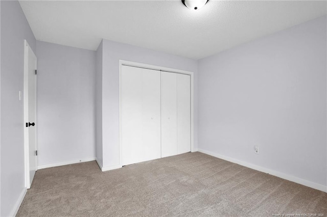 unfurnished bedroom with carpet floors, a closet, and baseboards