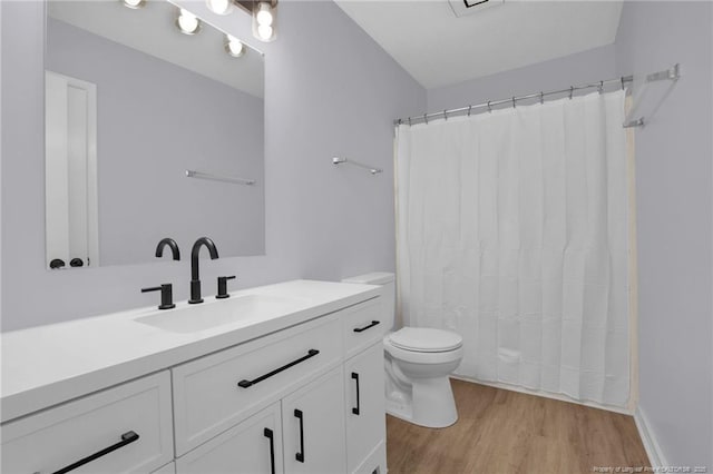 full bath featuring toilet, a shower with curtain, wood finished floors, and vanity