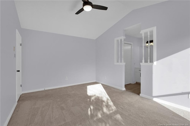 carpeted spare room featuring baseboards, vaulted ceiling, and a ceiling fan