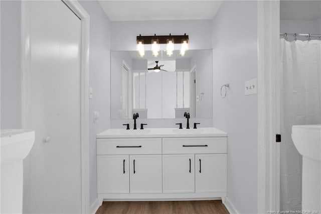 bathroom featuring ceiling fan, baseboards, a sink, and wood finished floors