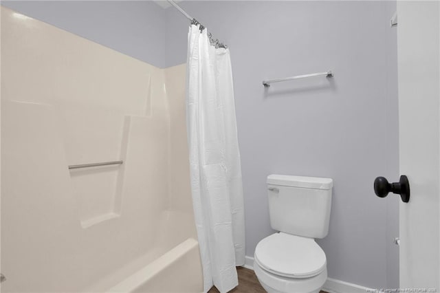 bathroom featuring shower / bath combo, toilet, and baseboards