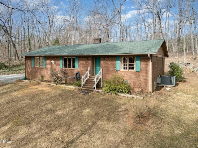 ranch-style house with a shingled roof, a chimney, crawl space, central air condition unit, and brick siding