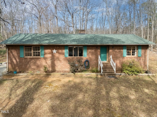 ranch-style home with entry steps, roof with shingles, a chimney, and brick siding