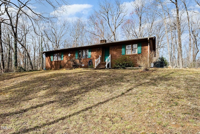 ranch-style house featuring entry steps, central AC unit, a front lawn, and brick siding