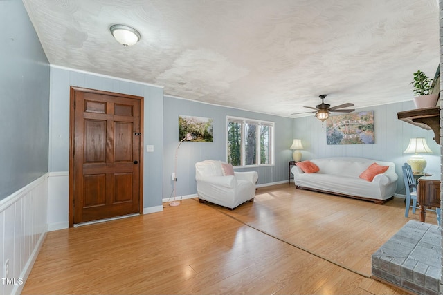 living area with a textured ceiling, light wood finished floors, and a ceiling fan