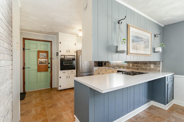 kitchen featuring freestanding refrigerator, a sink, gas cooktop, black oven, and a peninsula