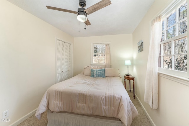 carpeted bedroom featuring ceiling fan, a closet, and baseboards