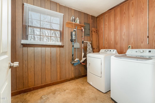 laundry room with laundry area, wood walls, independent washer and dryer, and electric panel